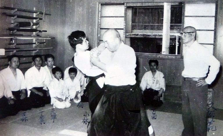 久琢磨の指揮の下、小林清弘師範に技をかける蒔田完一。左端に森恕師範、左から2番目に千葉紹隆（1973年5月）。